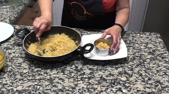 Servir el arroz en un aro para darle forma. Colocar los langostinos encima y añadir un poco de salsa.