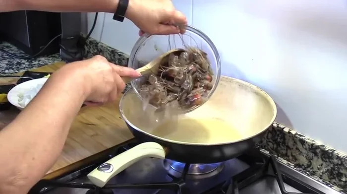Calentar aceite de oliva en un wok o sartén honda. Freír las cabezas y pieles de los langostinos hasta que suelten su jugo (aprox. 5 minutos).