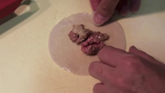 Humedecer el borde de la masa con agua y cerrar las empanadillas, formando ondas en los bordes. (92.68)