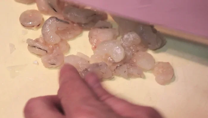 Picar finamente la cebolla y cortar las gambas en cuatro partes. (20.68)