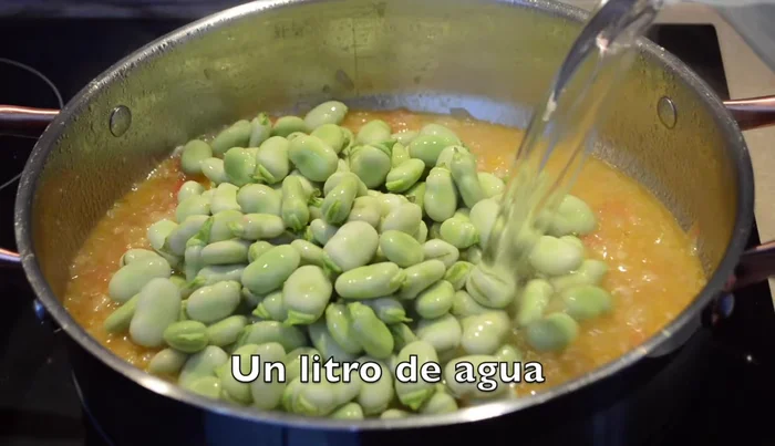 Añadimos las habas, 1 litro de agua, 1 litro de caldo, cúrcuma, la hoja de laurel y un poquito más de sal.