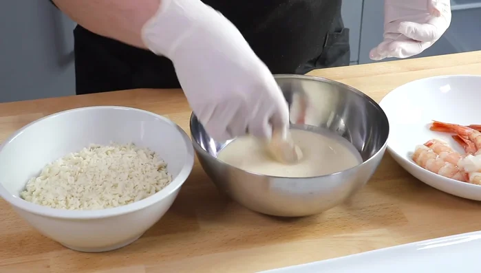 Pasar los gambones por la tempura, asegurándose de cubrirlos completamente.