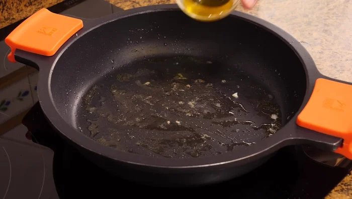 Añadir 1.5 cucharadas de aceite de oliva virgen extra a la misma cacerola. Agregar la cebolla picada y el ajo picado (300g) y sofreír hasta que esté listo.
