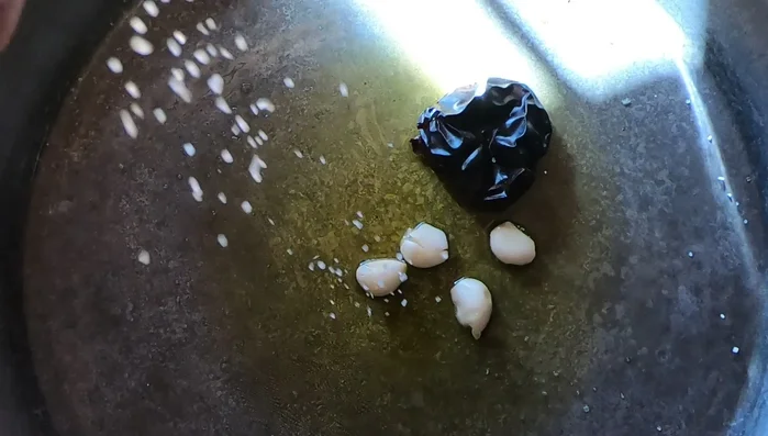 En la paella, calentar el aceite de oliva, añadir la ñora, los ajos y saltear durante un minuto para aromatizar el aceite.
