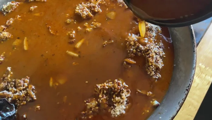 Agregar el caldo de pescado caliente (3 partes de caldo por 1 de arroz). Subir el fuego y mantener durante 5 minutos.