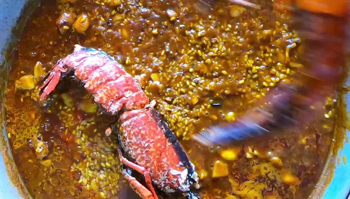 Retirar la ñora. Bajar el fuego a medio, colocar el bogavante boca abajo y añadir las gambas.