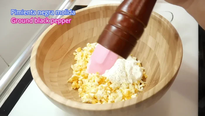 Añadir sal y pimienta negra molida al gusto. Mezclar bien, haciendo presión para romper las yemas del huevo.