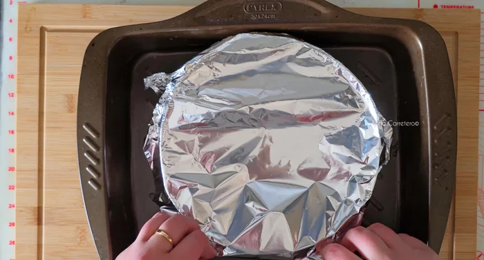 Tapar el molde y colocarlo en una bandeja apta para horno con 2 cm de agua hirviendo.