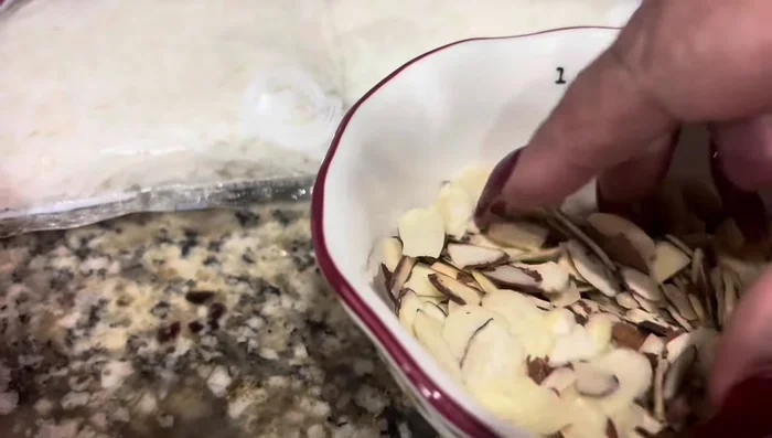 En un recipiente, mezclar la almendra fileteada, el coco rallado y la canela (opcional). Agregar agua caliente y dejar reposar por 15 minutos (53.8).