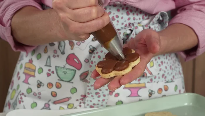 Rellenar las galletas con dulce de leche usando una manga pastelera.