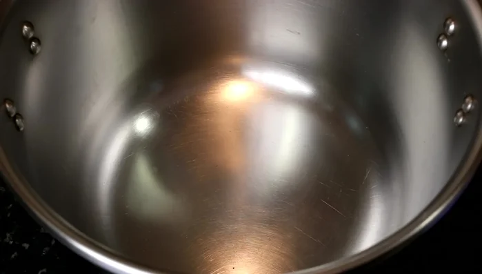 Poner una olla express a presión normal en el fuego. Añadir 60 ml de aceite de oliva y los ajos. Freír hasta que estén dorados (51.65).