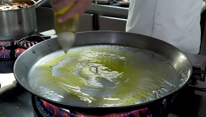 En una paella, añade un chorrito de aceite de oliva virgen extra. Añade la cebolla y el ajo. Sofríe hasta que estén blandos.