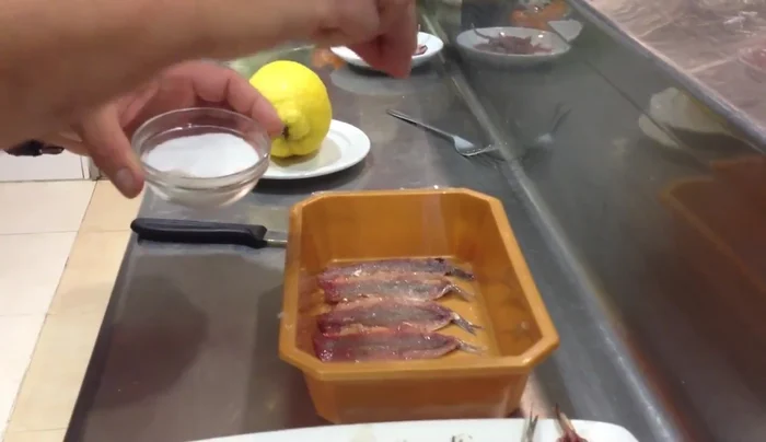 Marinar las anchoas: disponerlas en un taper, añadir sal y zumo de limón, cubrirlas completamente y dejar marinar durante 5 minutos. (165.04)