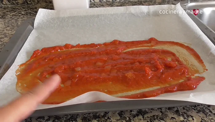 En una bandeja de horno, colocar una cucharada de salsa de tomate. (129.819)