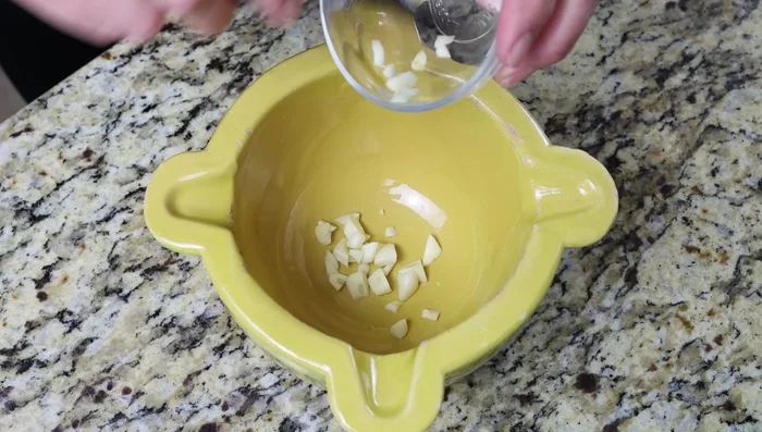 Para el alioli, machaca 2 dientes de ajo, 1/4 cucharadita de azafrán y sal en un mortero.