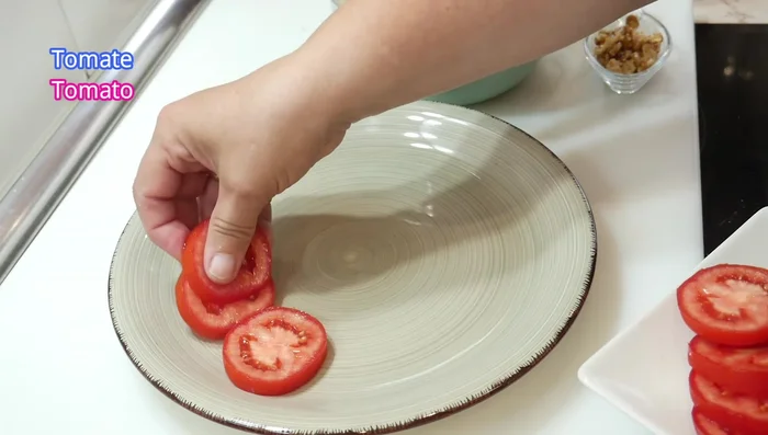 Montar la ensalada: Colocar rodajas de tomate en un plato como base. Agregar sal al gusto.