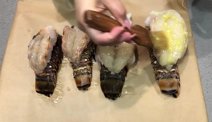 Bañar generosamente las langostas con la mezcla de mantequilla, limón y ajo, usando una brocha.
