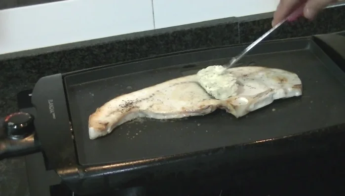 Agrega la mantequilla: Una vez sellado, coloca un trozo de la mantequilla de finas hierbas sobre el filete. Deja que se derrita con el calor residual de la plancha. Dale la vuelta al filete y añade otro trozo de mantequilla.