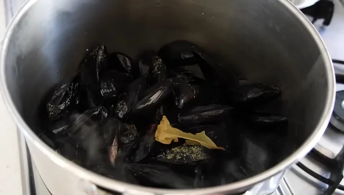 En una cazuela, abrir las clochinas a fuego alto con las hojas de laurel durante unos 2 minutos, removiendo y retirando las que se abren. Reservar el caldo.