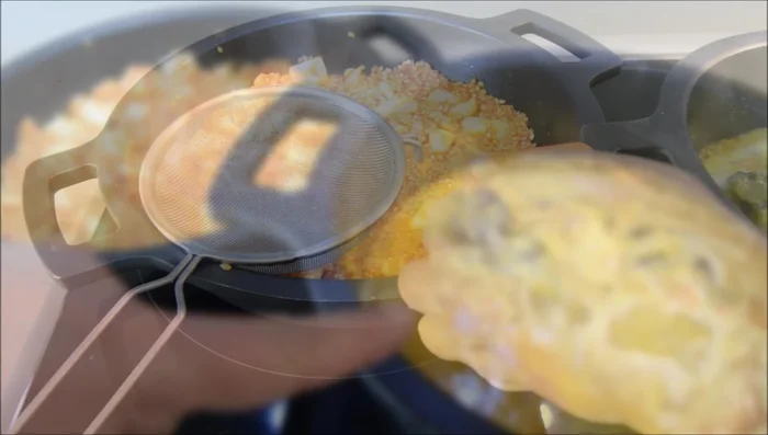 Añadir el caldo hirviendo al arroz. Distribuir el caldo por la paella.