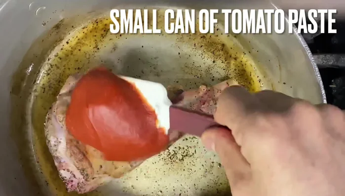 Untar el pernil con pasta de tomate por todos los lados y seguir sofriendo, volteándolo, para que la pasta de tomate ayude con el sabor y el color.