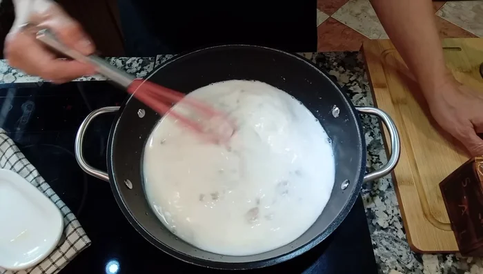 Agregar la leche poco a poco, sin dejar de remover con las varillas hasta obtener una textura cremosa sin grumos. Agregar nuez moscada si se desea.