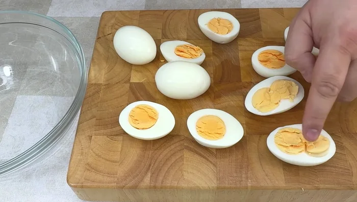 Pelar y cortar los huevos por la mitad. Retirar las yemas y reservar algunas para decorar.