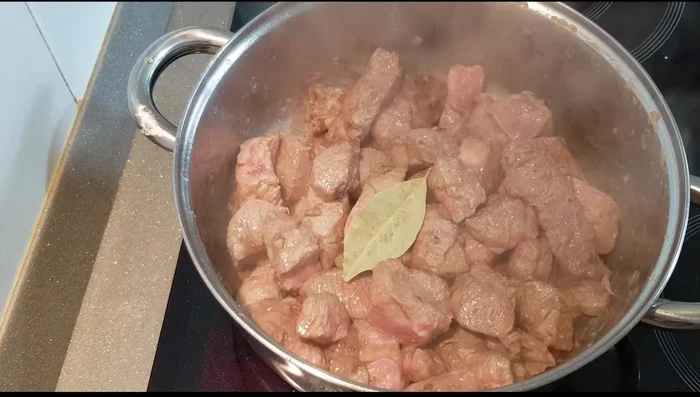 Agregar la hoja de laurel, orégano, sal, pimienta y la zanahoria troceada a la carne sellada.