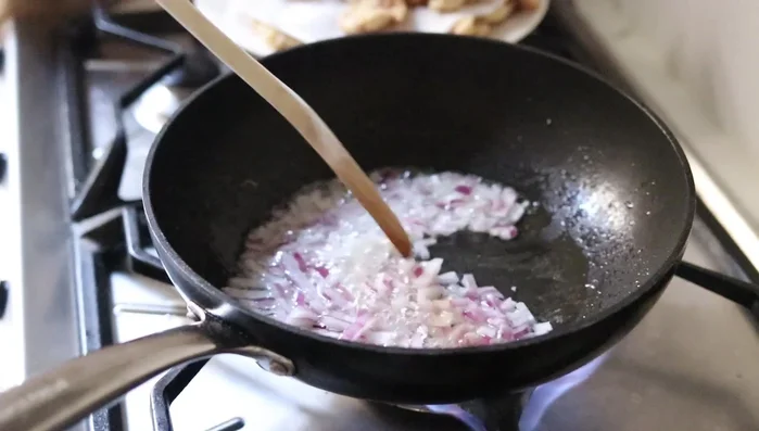 Preparar la salsa agridulce: sofreír cebolla y morrones en aceite caliente. [199.03]