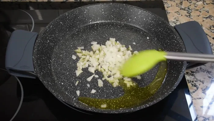 En una paella, sofreír la cebolla con un poco de sal hasta que esté transparente. (173.54)