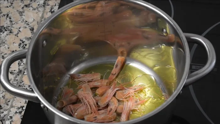 Preparar el caldo: En una olla grande, sofreír las cabezas de gambas, tentáculos y aletas de calamares en aceite de oliva hasta que estén doradas. (44.62)