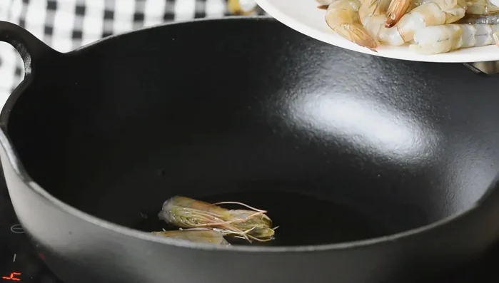 En un recipiente a fuego medio, calentar un poco de aceite y freír las cabezas de los langostinos reservadas hasta que cambien de color. Retirarlas.