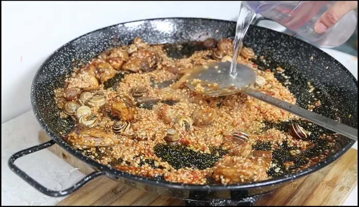Añadir agua hasta la marca de los tornillos de la paella. (158.599)