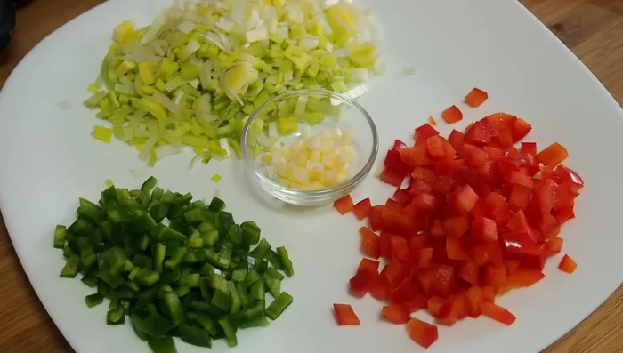 Picar finamente el puerro, el pimiento verde y rojo, y los ajos.