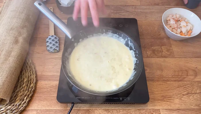 Si se desea, pasar la bechamel por la batidora para que la cebolla no se note. Agregar la mezcla de vieiras y gambas. Cocinar durante 1 minuto.