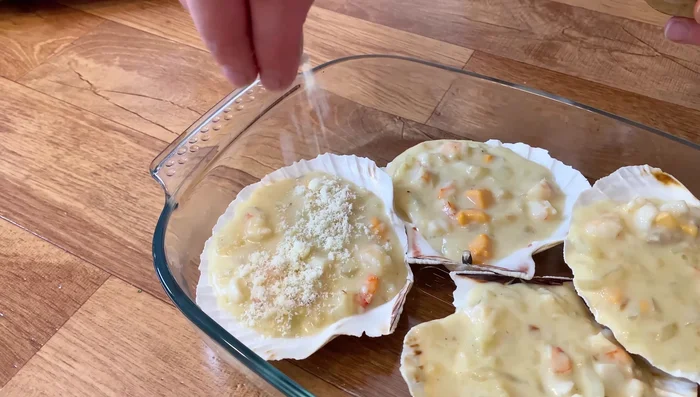 Espolvorear queso parmesano rallado sobre cada vieira. Gratinar en el horno con calor arriba durante 5 minutos.