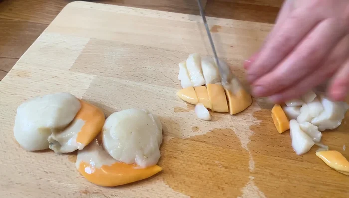 Picar la cebolla finamente. Cortar las vieiras en trozos pequeños. Picar las gambas peladas en trozos similares a los de las vieiras. Mezclar las vieiras y las gambas en un bol.