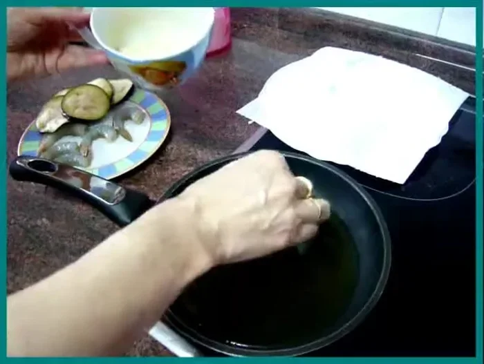 Freír los langostinos y las berenjenas en abundante aceite caliente hasta que estén dorados por ambos lados.
