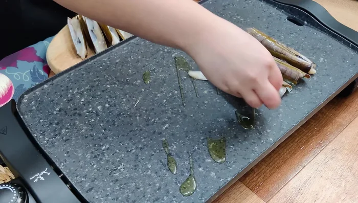 Colocar las navajas en la plancha caliente con la concha hacia arriba. Cocinar durante 2 minutos.