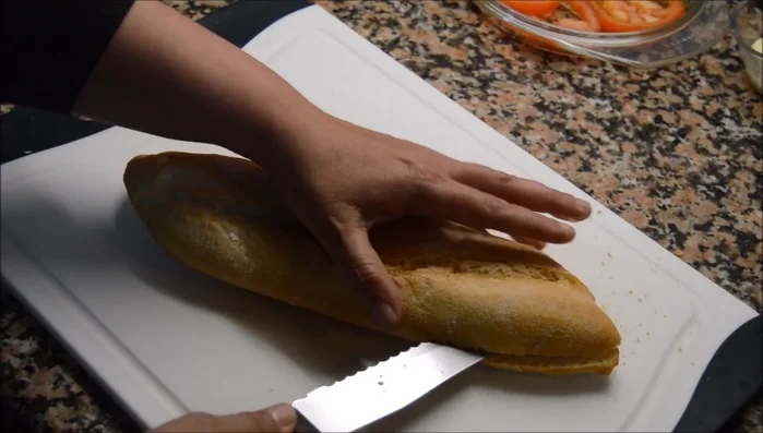 Cortar el pan por la mitad con un cuchillo de sierra. Tostar ligeramente el pan en una plancha o sartén.