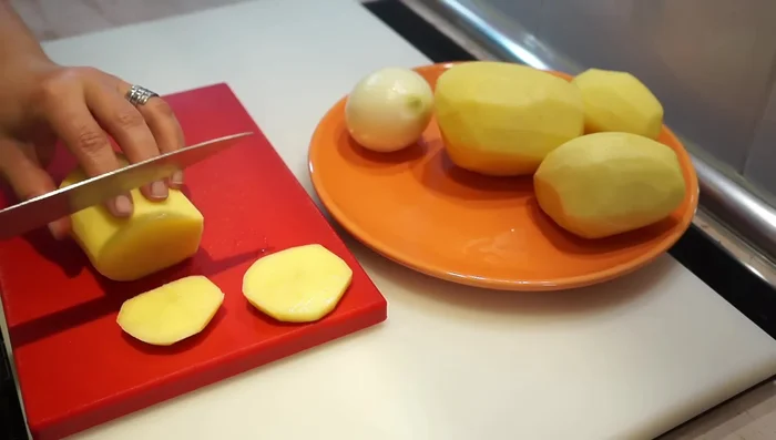 Pelar y cortar las patatas en rodajas gruesas (aproximadamente 1 cm) y la cebolla en juliana.