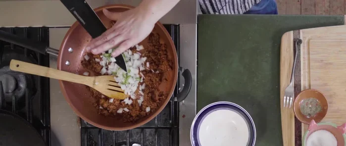 Agregar la cebolla y el chile serrano al chorizo. Cocinar hasta que las cebollas estén tiernas.