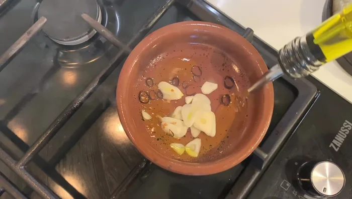 Añadir el ajo y el chile a la olla caliente. Verter inmediatamente el aceite de oliva virgen extra.