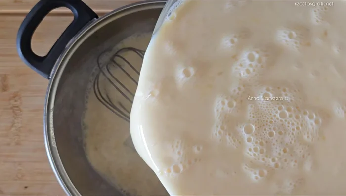 Agregar la mezcla de leche, huevo y yemas a la leche con azúcar, remover sin parar hasta que espese.