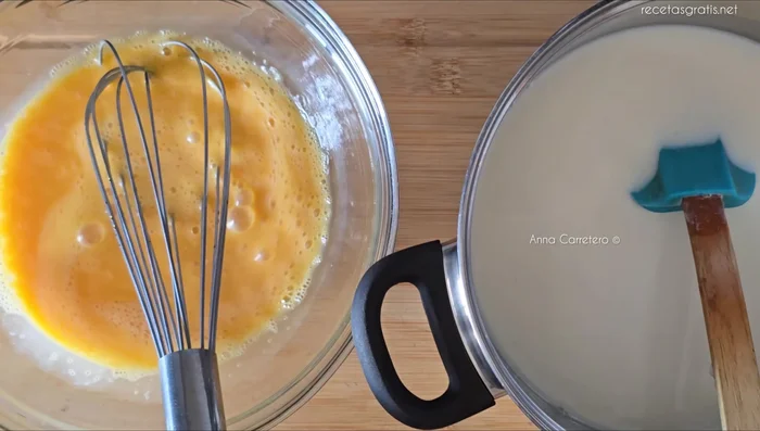 Agrega lentamente la leche tibia a la mezcla de huevos y vainilla, mezclando suavemente. Pasa la mezcla por un colador para eliminar posibles grumos.