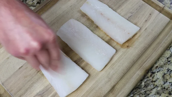Sazonar los filetes con sal marina y pimienta negra por ambos lados (68.6). Cortar cada filete en dos (77.72).