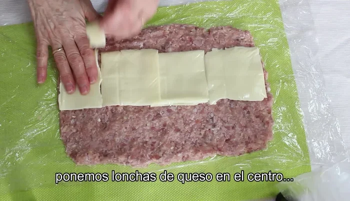 Colocar las lonchas de queso en el centro y enrollar con ayuda del film transparente, formando un rollo apretado.