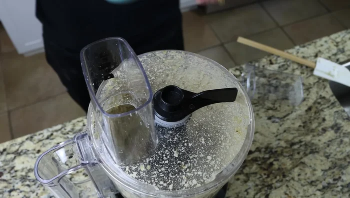 Agregar agua (2-3 cucharadas, 30-45ml), una cucharada a la vez, mientras el procesador de alimentos está funcionando, hasta lograr la textura deseada. Probar y ajustar la sazón.