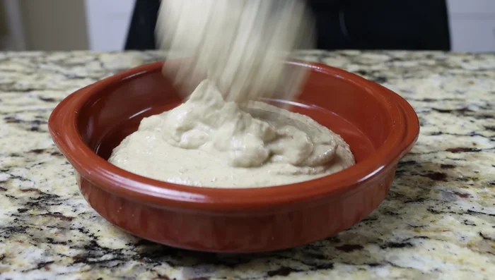 Transferir el hummus a un recipiente poco profundo. Crear curvas en la superficie con el dorso de una cuchara. Decorar con las lentejas reservadas, un chorrito de aceite de oliva y cilantro picado.