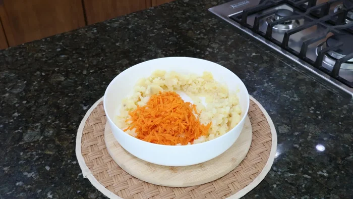 Rallar la zanahoria y agregarla a las papas junto con el calabacín escurrido, el queso rallado y el pan molido o harina de trigo.